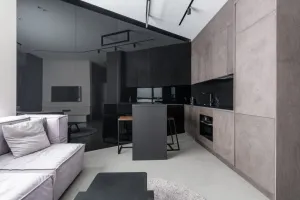 Nowoczesna łazienka z prysznicem walk-in, czarną armaturą i drewnianym stołkiem, utrzymana w jasnej, minimalistycznej estetyce.